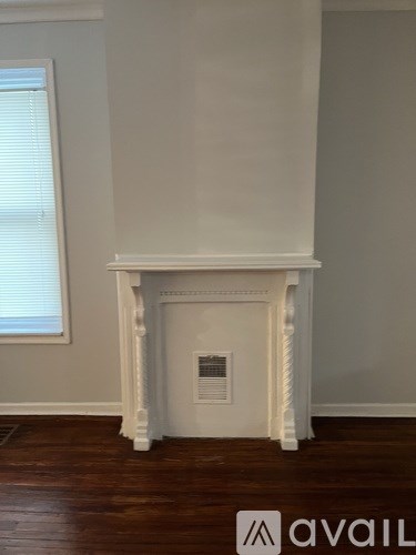 A white fireplace in a room with wooden floors.