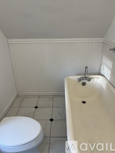 A white toilet sits next to a white sink in a small bathroom.
