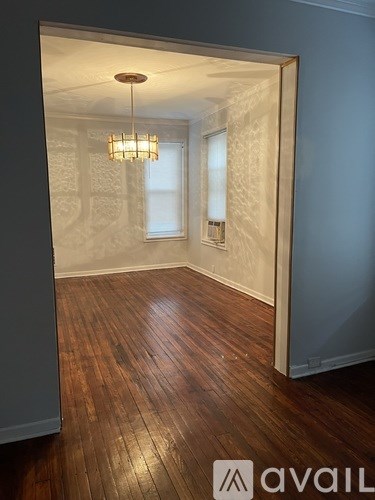 A room with wooden floors and a chandelier hanging from the ceiling.