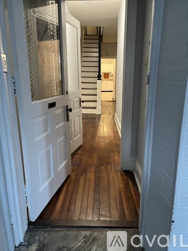 A hallway with a wooden floor and a white door.