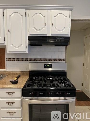 A kitchen with a stove top oven and a range hood above it.