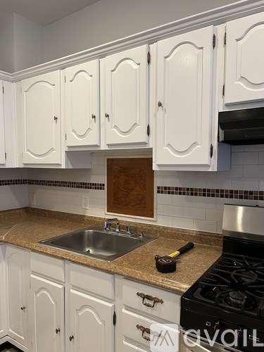 A kitchen with white cabinets and a black stove top.