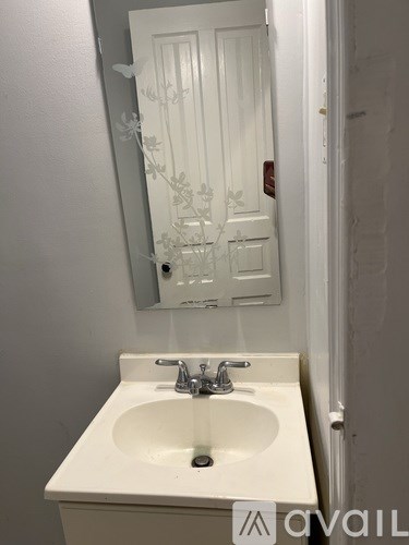 A white sink in a bathroom with a mirror above it.