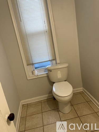 A white toilet in a bathroom with a window above it.