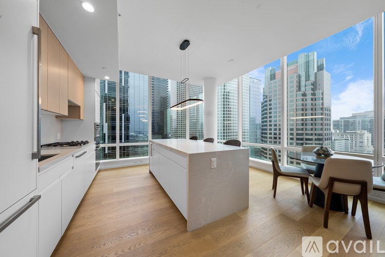 A modern kitchen with wooden floors and a large window overlooking the city.