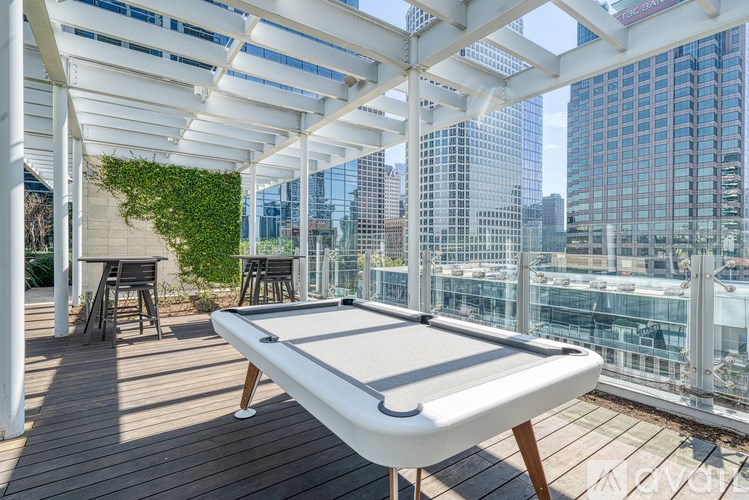 A pool table is on a wooden deck with a white canopy.