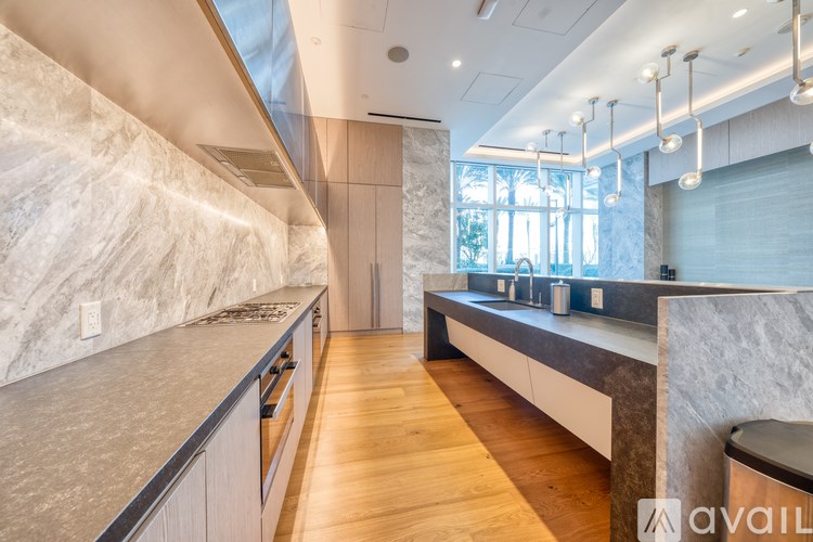 A modern kitchen with a marble backsplash and wooden floors.