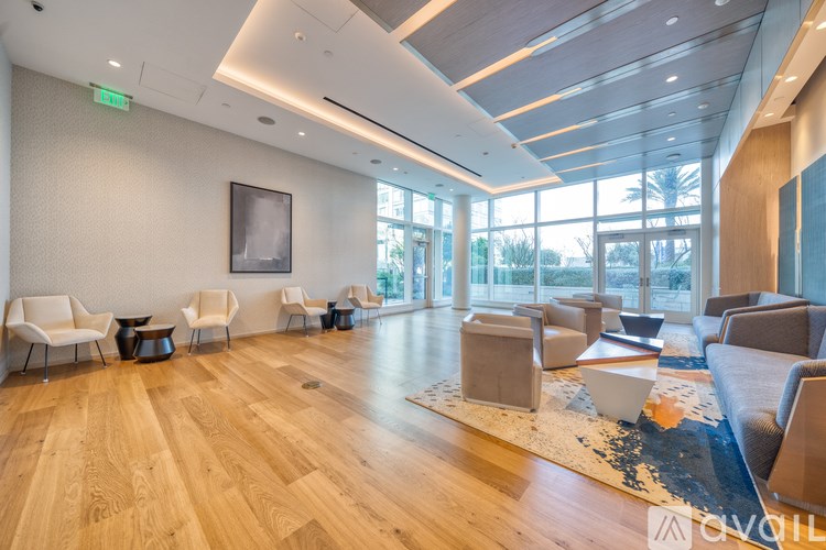 A spacious waiting room with wooden floors and white chairs.