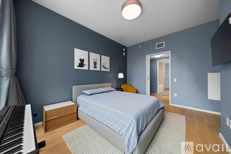 A bedroom with a bed, a piano, and pictures on the wall.
