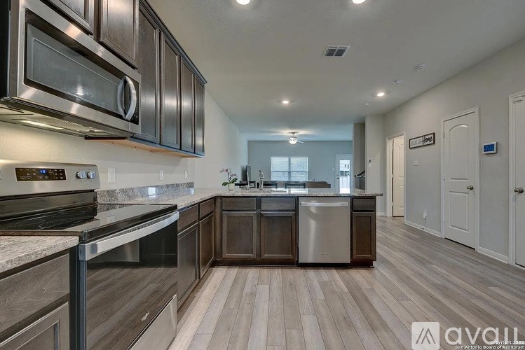 A modern kitchen with dark wood cabinets and stainless steel appliances.