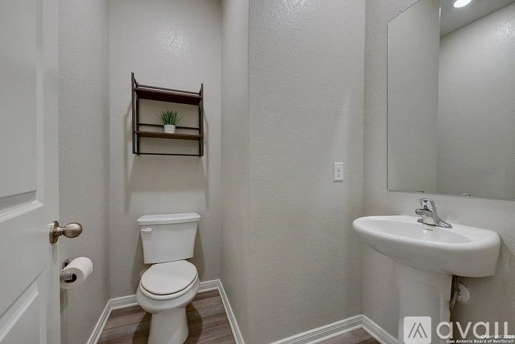 A white toilet sits next to a white sink in a small bathroom.