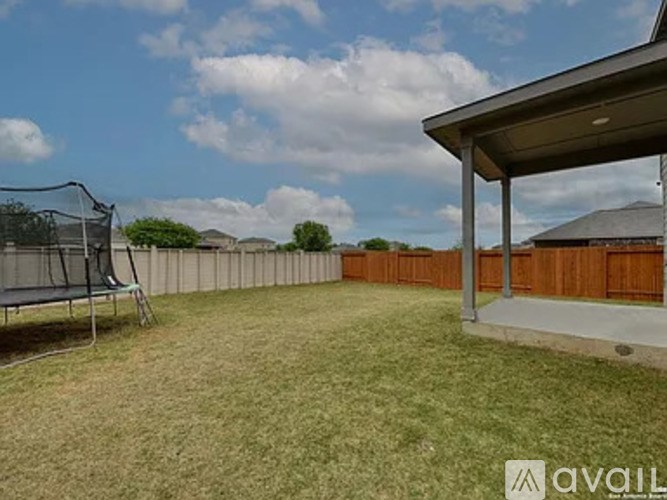 A backyard with a trampoline and a wooden fence.