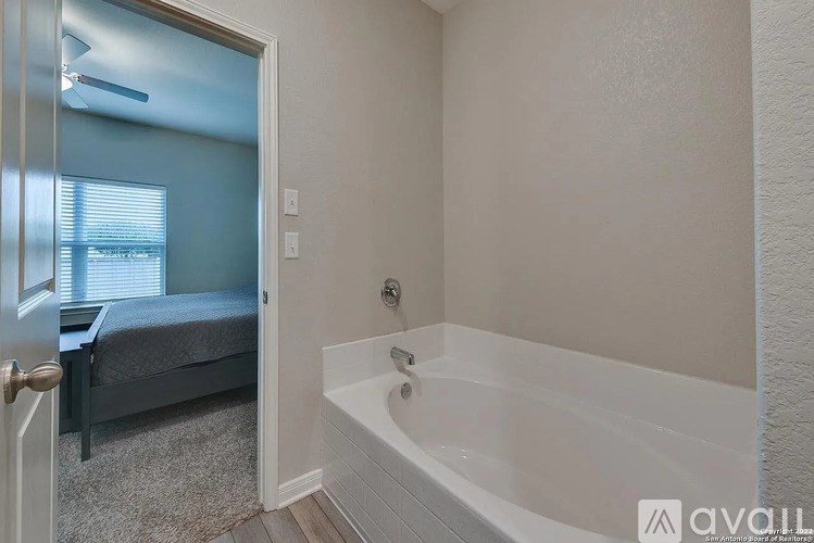 A bathroom with a white tub and a window with blinds.