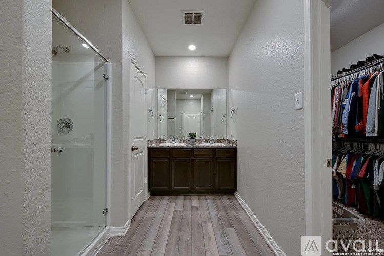 A hallway with a wooden floor and a vanity with a mirror.