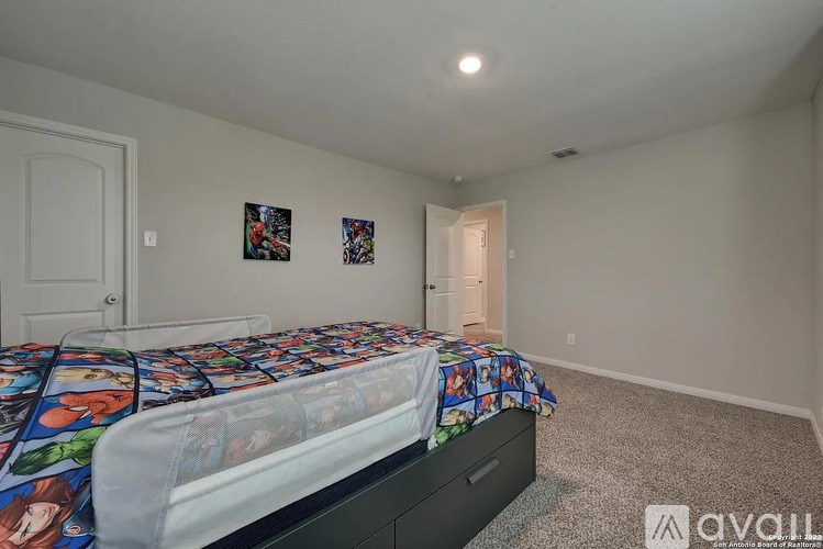 A bedroom with a bed, carpeted floor, and two pictures on the wall.