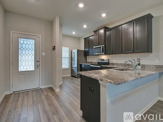 A kitchen with dark brown cabinets and a granite countertop.
