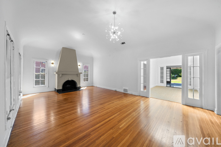 A spacious room with wooden floors and a fireplace.