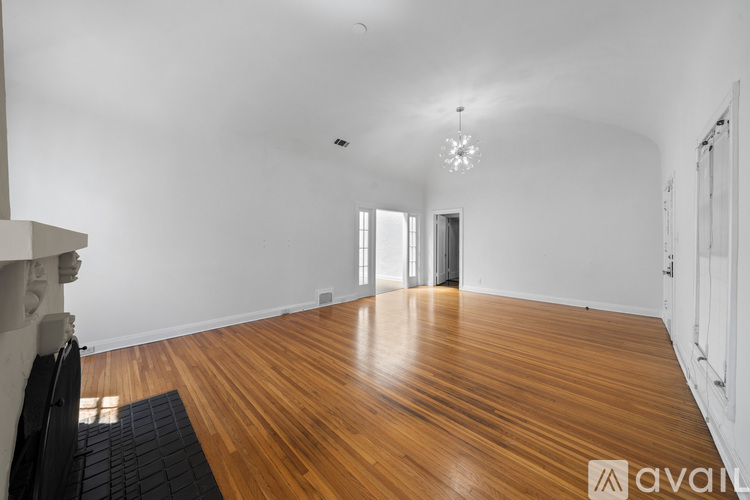 A room with wooden flooring and a chandelier hanging from the ceiling.