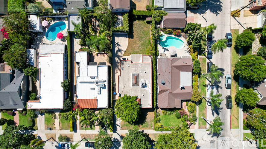 A bird's eye view of a residential area with houses, trees, and a pool.