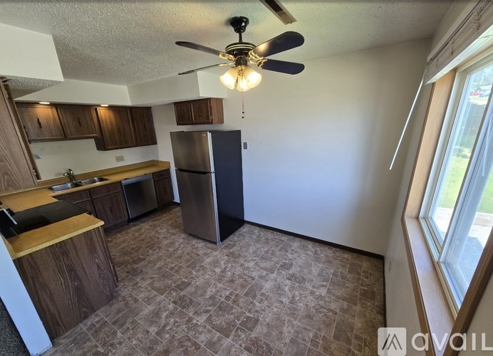 A kitchen with a refrigerator, sink, and cabinets.