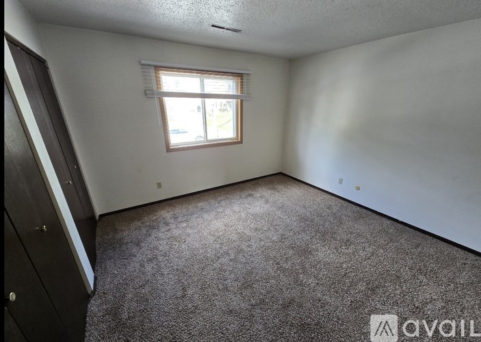 A room with a carpeted floor and a window with blinds.
