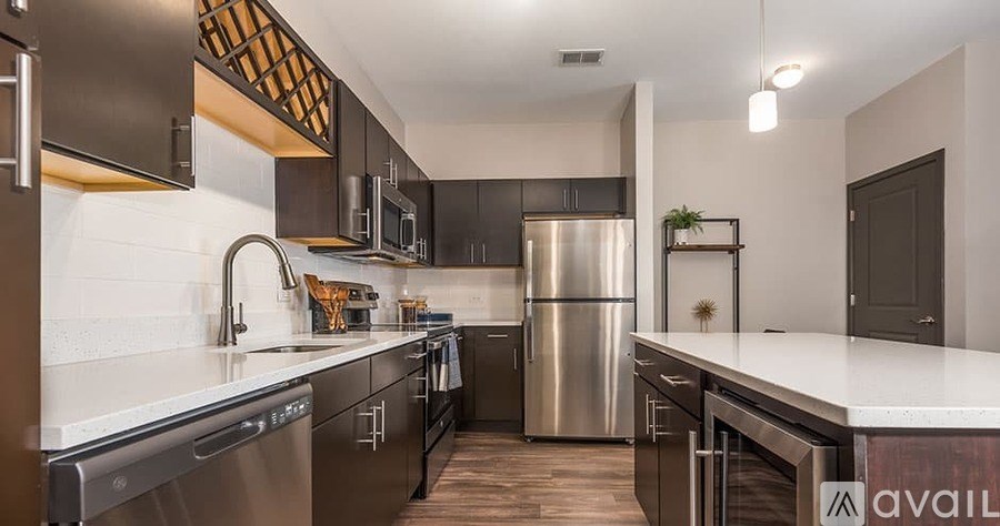A modern kitchen with stainless steel appliances and wooden flooring.