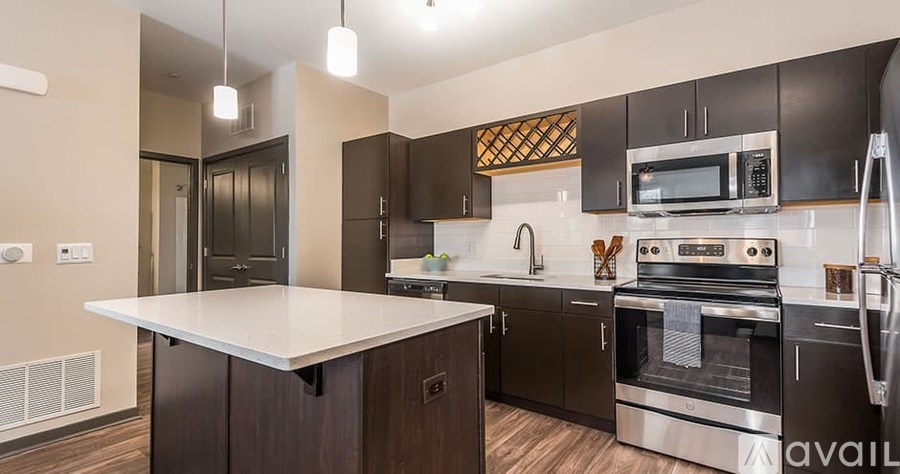 A modern kitchen with dark brown cabinets and stainless steel appliances.