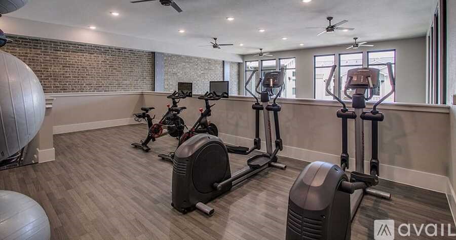 A gym with a row of treadmills and elliptical machines.