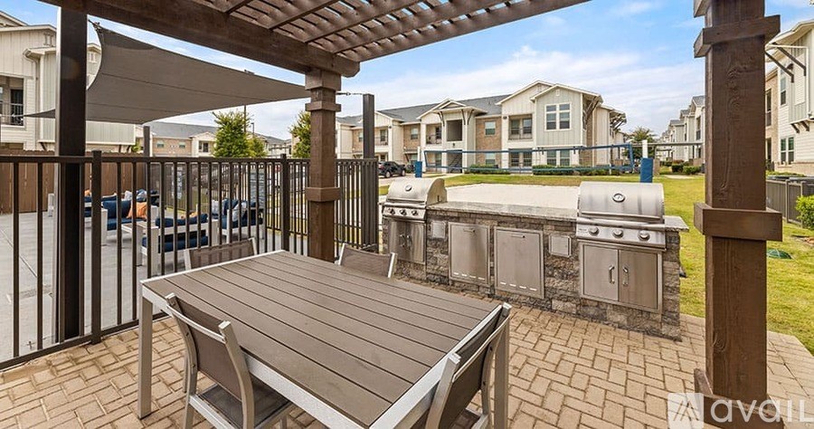 A wooden table is set under a pergola in a patio area.