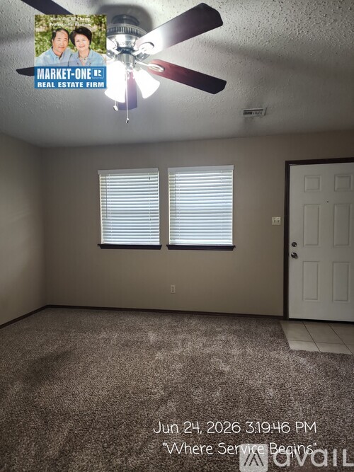 A room with a ceiling fan and two windows.