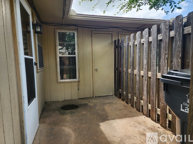 A wooden fence surrounds a small building with a door and windows.