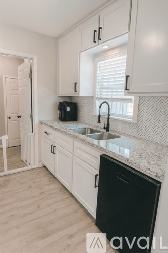 A kitchen with white cabinets and a black dishwasher.