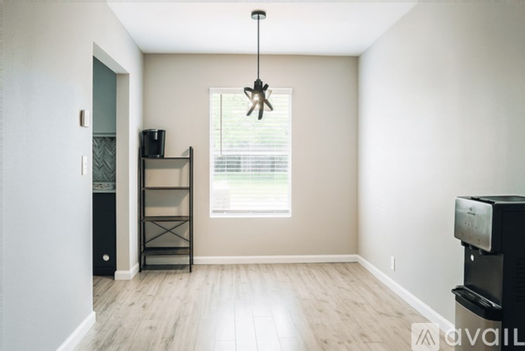 A room with a television, a window with blinds, and a wooden floor.