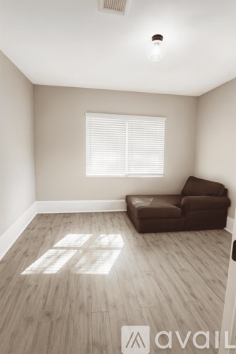 A room with a brown couch and wooden flooring.