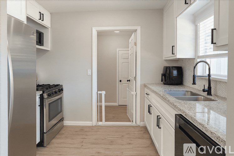 A kitchen with white cabinets and a stainless steel refrigerator.
