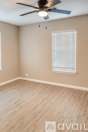 A room with a ceiling fan and a window with blinds.