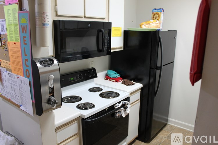 A kitchen with a black fridge, white stove, and black microwave.