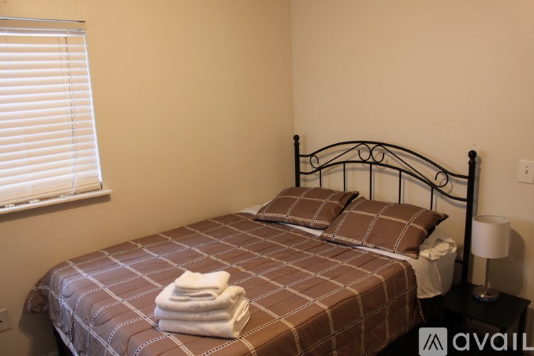 A bed with a brown checkered comforter and two pillows with a white towel folded on top.