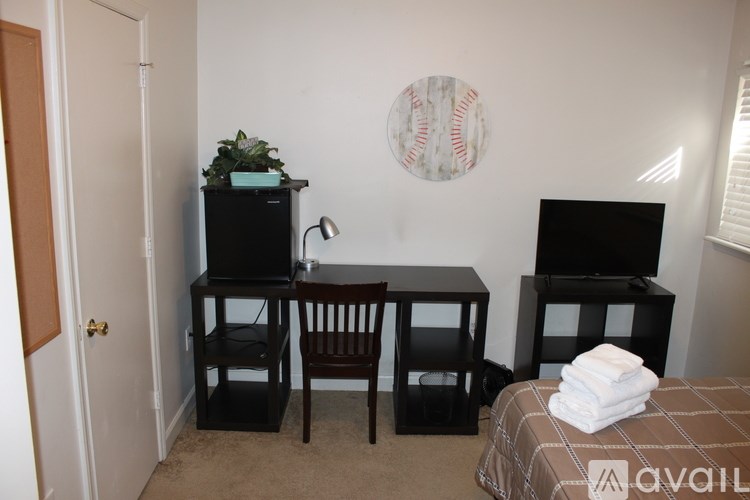 A room with a bed, a desk with a chair, and a television.