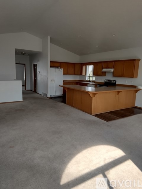 A large, empty kitchen with wooden cabinets and a central island.