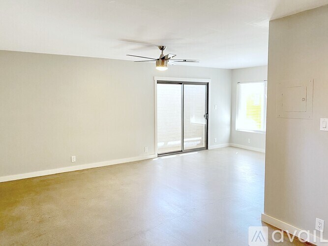 A spacious room with a ceiling fan and sliding glass doors.