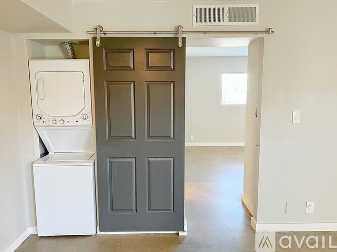 A white washing machine is in front of a grey door.