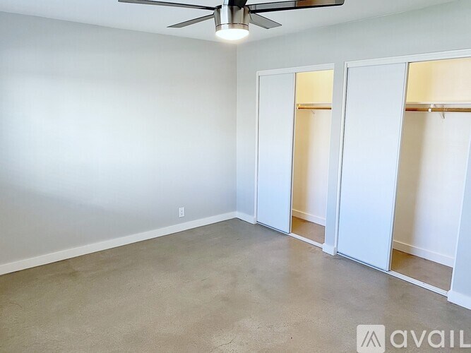 A room with a ceiling fan and two open doors.