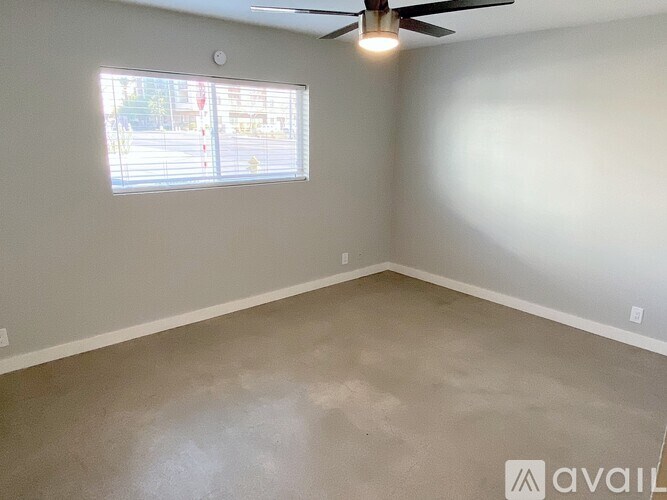 A room with a ceiling fan and a window with blinds.