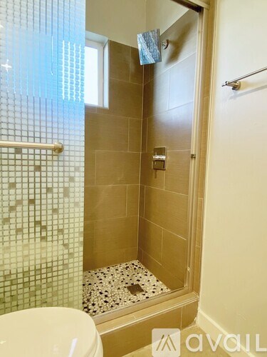 A bathroom with a toilet, a shower with a glass door, and a tiled floor.