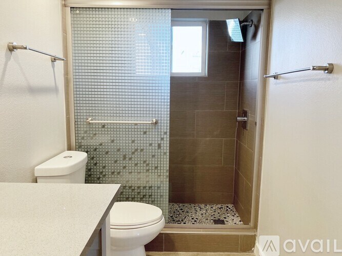 A bathroom with a toilet, a shower with a glass door, and a tiled wall.