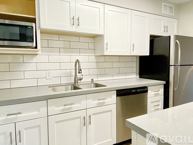 A kitchen with white cabinets and a black refrigerator.