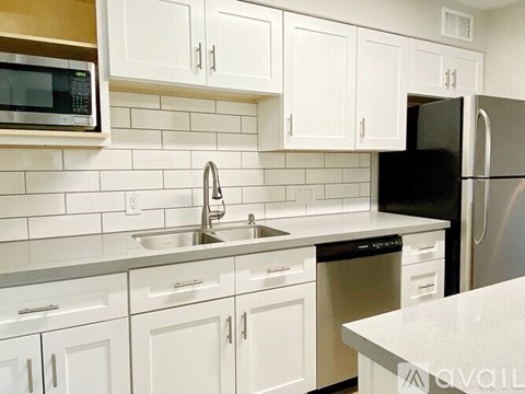 A kitchen with white cabinets and a black refrigerator.