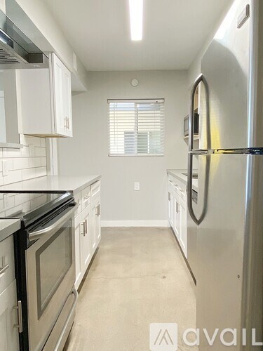 A kitchen with white cabinets and a stainless steel refrigerator.