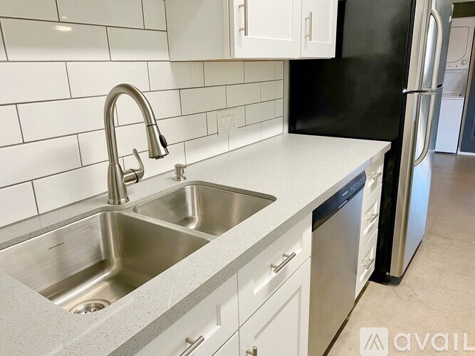 A kitchen with a sink and a black refrigerator.